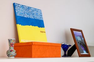Auf einer Box steht ein selbst gemaltes Bild in blau-gelb