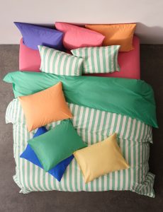 Grün-weiss gestreifte Bettwäsche mit Kissen in bunten Farben