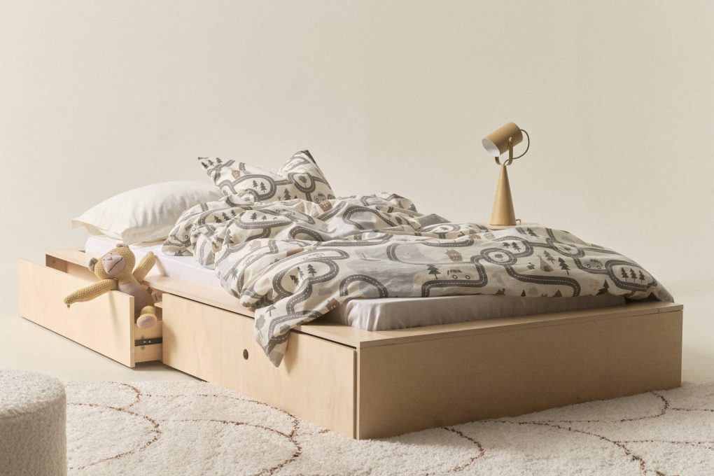 ein freistehendes Bett mit Kuschelaffe, Lampe in Beige und gemustertem Teppich